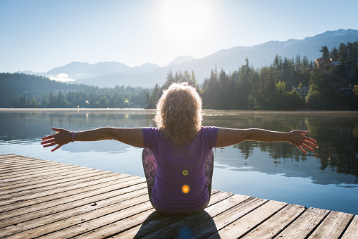 Senior woman doing morning yoga at a mountain lake