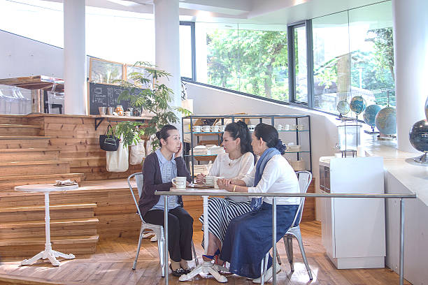 Three women chatting at a coffee shop Three women are sitting and chatting gently at a cafe shop. A woman is speaking and the others carfully lisening. They look like nervous. Mya be they are chatting there anguish of heart. stay at home saying stock pictures, royalty-free photos & images