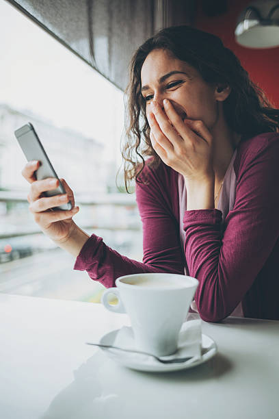 istock Girl laughing at a message in a coffee shop 578791382