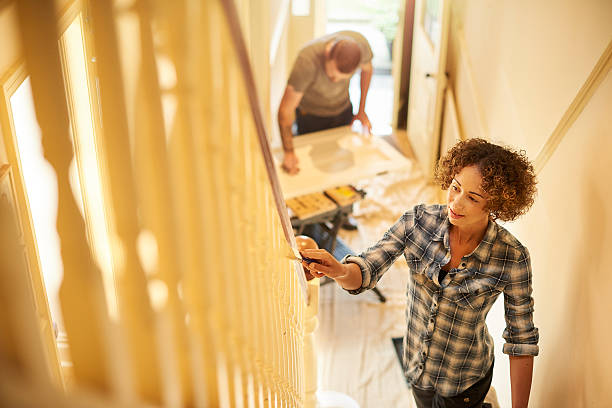 fresh paint for the old house A young couple doing up their hallway in the old house they have bought . They are sitting on the dust sheets and painting the woodwork in their old house. restoring home improvement house home interior stock pictures, royalty-free photos & images