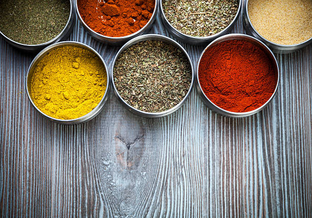 Spices and herbs in metal containers on wooden table