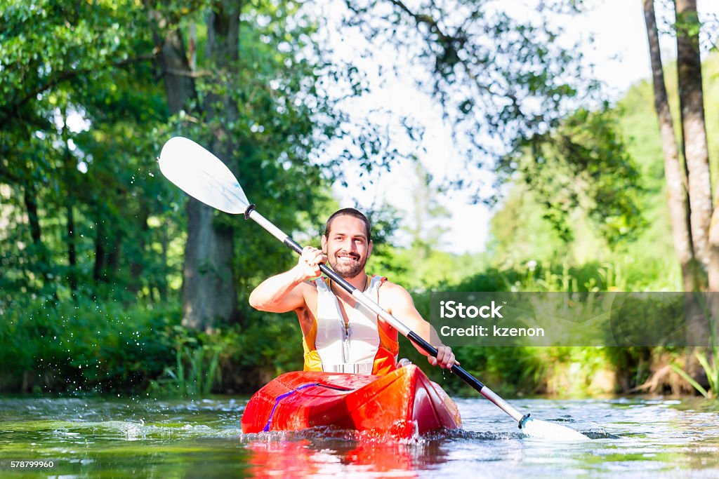 Man paddling with canoe on forest river Activity Stock Photo