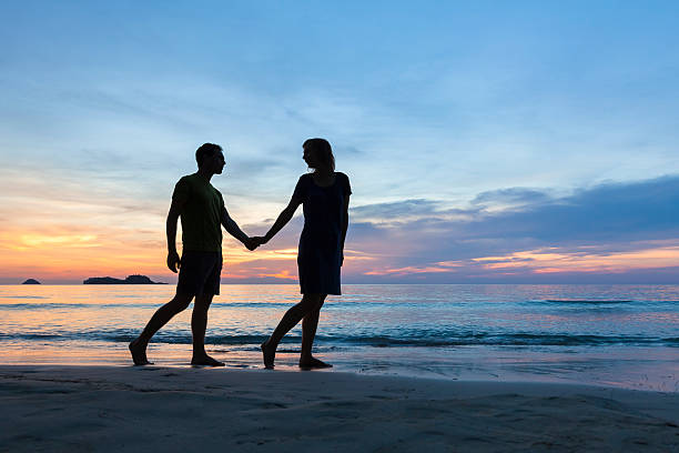 istock Happy romantic couple walking on the beach at sunset 578801026