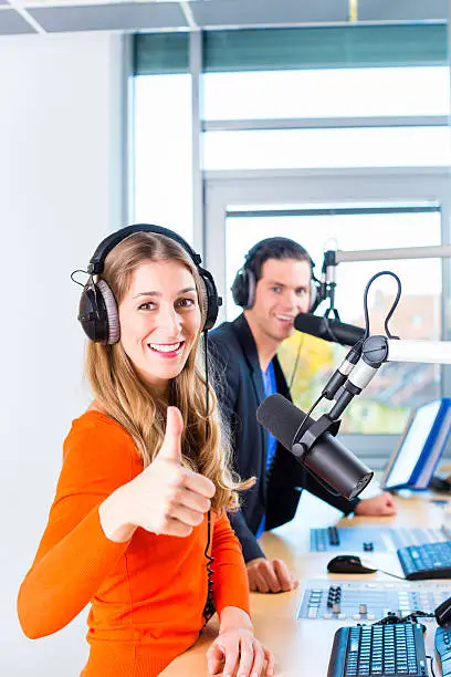 Presenters or moderators - man and woman - in radio station hosting show for radio live in Studio