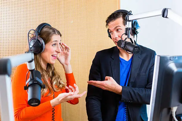 Presenters or moderators - man and woman - in radio station hosting show for radio live in Studio