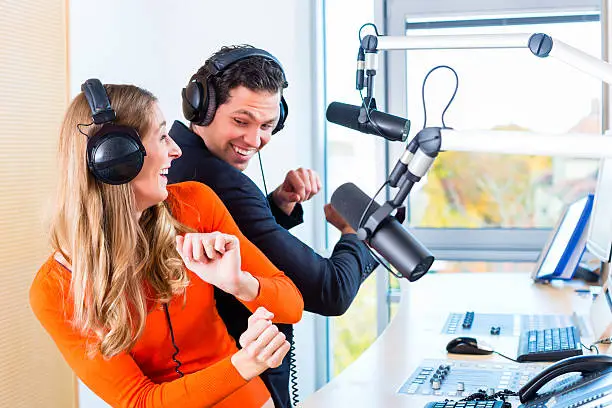 Presenters or moderators - man and woman - in radio station hosting show for radio live in Studio