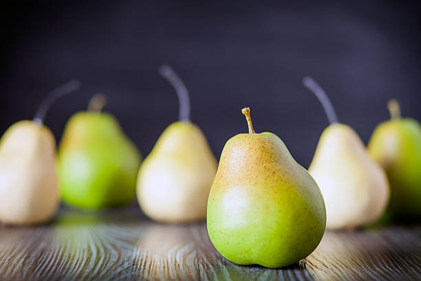 istock Green pears on wooden table dark background front view 578801724
