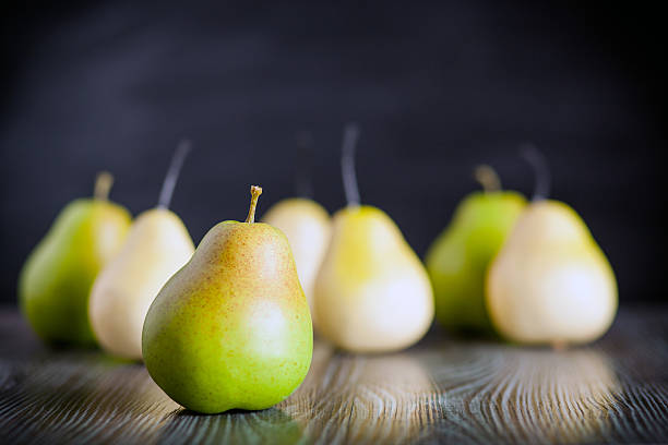 istock Green pears on wooden table dark background front view 578801774