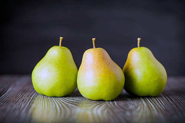 istock Green pears on wooden table dark background front view 578801836