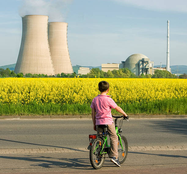 ragazzo sulla bici in canola field e centrale nucleare - nuclear power station nuclear energy child nuclear reactor foto e immagini stock