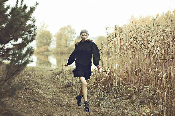 Fashion model woman run in black dress. Nature background. stock photo