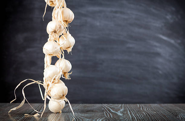 string of garlic on wooden table dark background copy space - garlic hanging string vegetable imagens e fotografias de stock