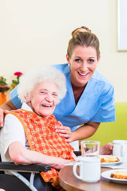 istock Nurse with senior woman helping with meal 578805496