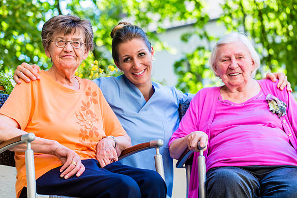 infermiera geriatrica che chiacchiera con donne anziane - nursing home senior adult group of people home caregiver foto e immagini stock