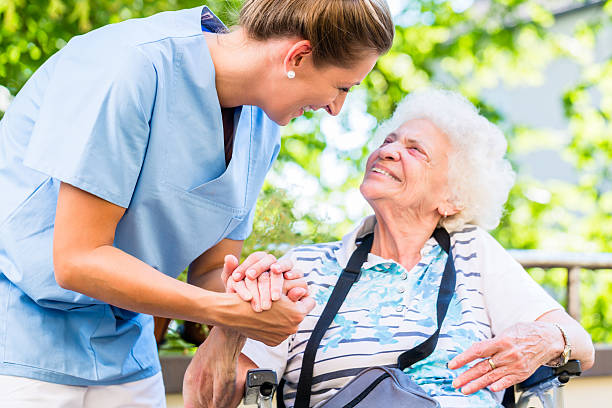 krankenschwester hält hand der seniorin im rentenheim - altersheilkunde stock-fotos und bilder