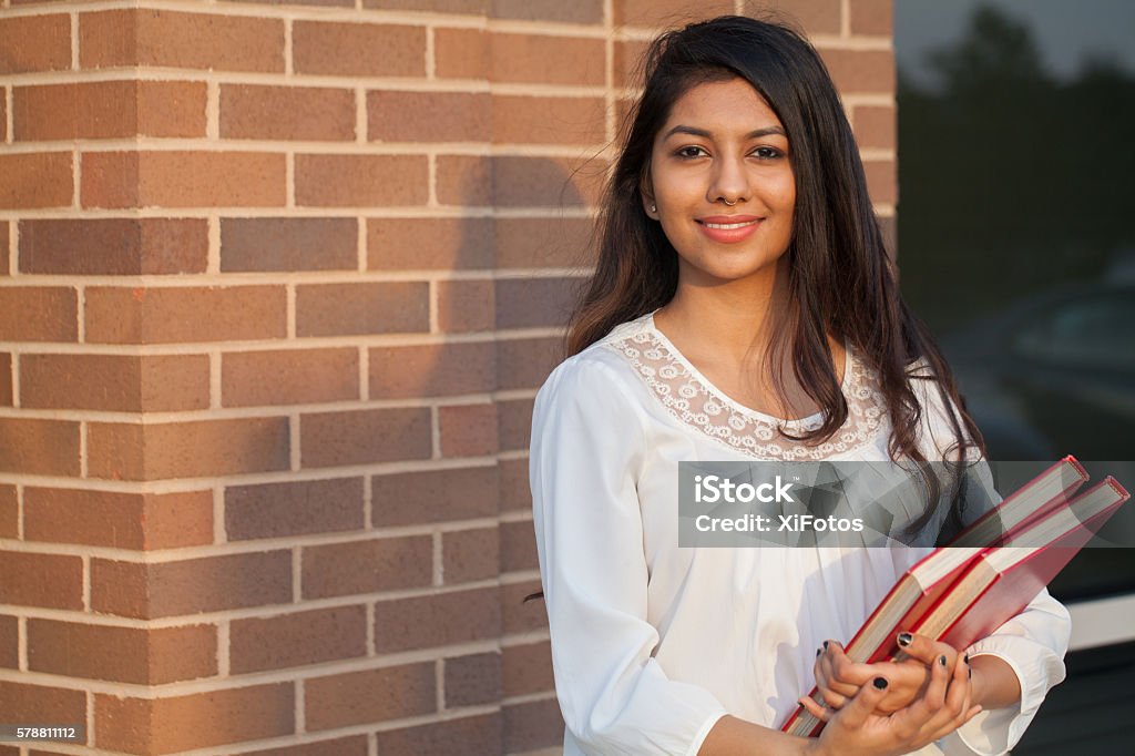 Smiling female young college student of Indian ethnicity Smiling female young college student of Indian ethnicity carrying backpack and holding books Indian Ethnicity Stock Photo