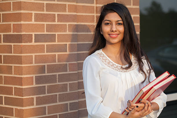 Smiling female young college student of Indian ethnicity Smiling female young college student of Indian ethnicity carrying backpack and holding books pakistan photos stock pictures, royalty-free photos & images
