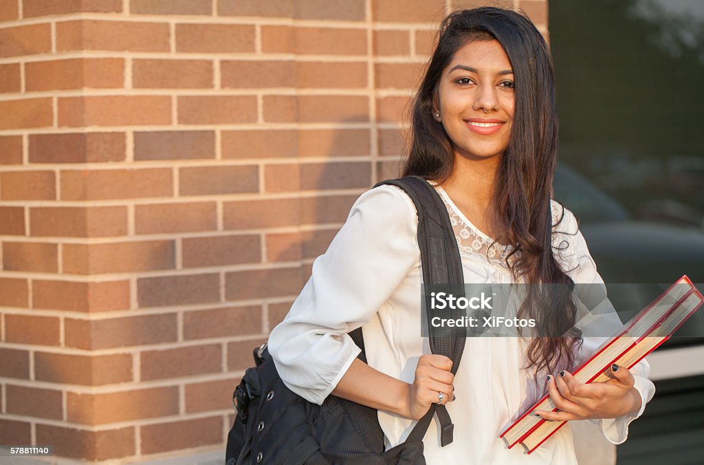 Smiling female young college student of Indian ethnicity Smiling female young college student of Indian ethnicity carrying backpack and holding books Indian Ethnicity Stock Photo