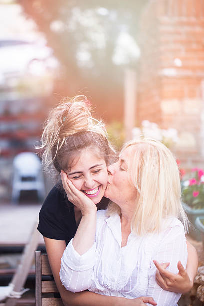 Mother kissing her daughter stock photo