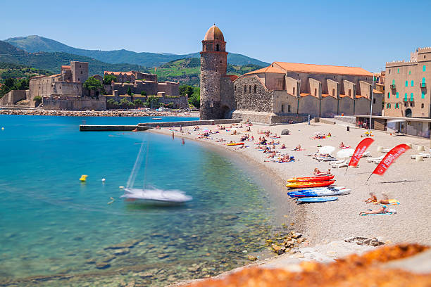 Skyline of Collioure, France Collioure, France - June 28, 2016. View of the picturesque Collioure, situated in the Département Pyrénées-Orientales. Château Royal in the centre of the picture. The beach is highly frequented by tourists and natives. Pyrenees Mountain Range in the background. Long exposed photography. collioure stock pictures, royalty-free photos & images