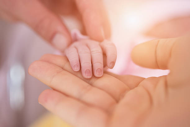 istock mother's hand holding babies hand 578813786