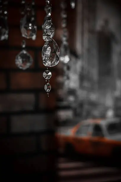 Chandelier glass hangs in the foreground against a backdrop of blurred brick wall and street life