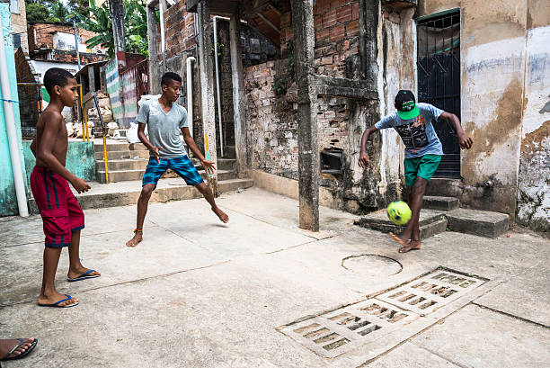 Boys playing football in the poor neighbourhoood, Salvador, Bahia, Brazil Salvador, Bahia, Brazil - September 19, 2015: Boys playing football in the poor neighbourhood of the Gentois community in Federacao district favela stock pictures, royalty-free photos & images