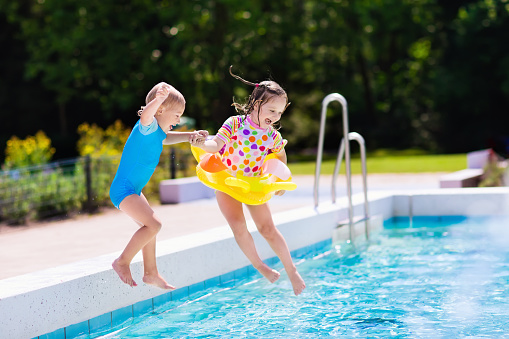 Happy little kids jumping into swimming pool