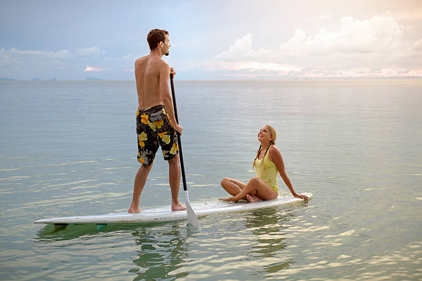 istock Happy couple surfing together on paddle board at sunset 578829504