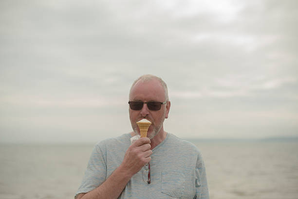 istock Smiling  man eating ice-cream by the ocean 578833784