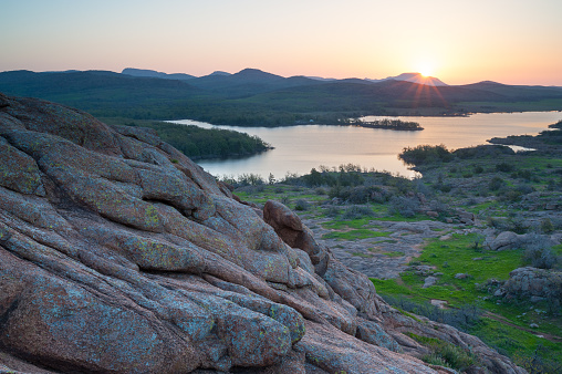 Mount Scott is seen in the background with the sun rising over it. The picture is taken from on top of Little Baldy in the Wichita Mountains of Oklahoma.