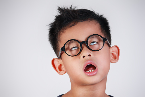Portrait of Asian boy with glasses showing very lazy unhappy bored and tired gesture