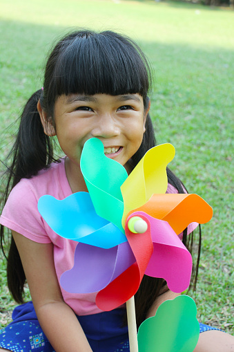 Little girl with colorful pinwheel in the park, spring time