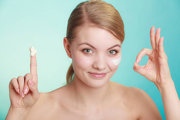 istock woman applying cream on her skin face. 579127856