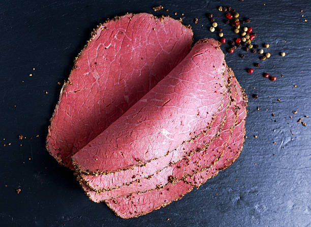 istock Peppered roast beef pastrami slices on paper with grains of 579127960
