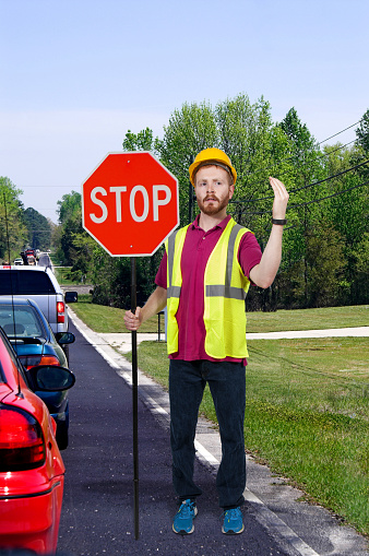 Man flagman holding a stop sign to halt traffic