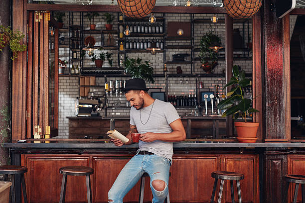 istock Modern young man reading a book in cafe 579128416