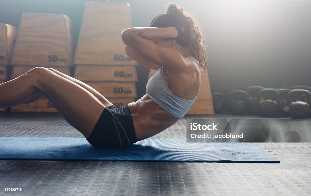 Fitness woman doing abs crunches Sporty young female athlete on yoga mat doing situps in gym. Fitness woman doing abs crunches. Sit-ups Stock Photo