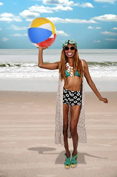 Beautiful young black woman holding a beach ball