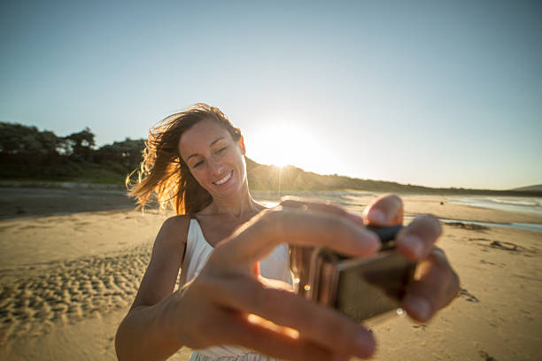ビーチで若い女性はウェアラブルカメラを使用して自分撮りを取ります - australia photographing camera beach ストックフォトと画像