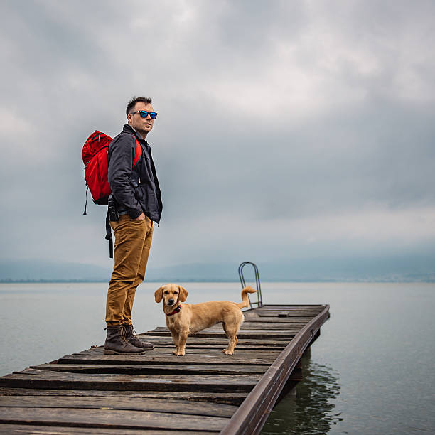 istock Man and his dog standing on wooden dock 579131550