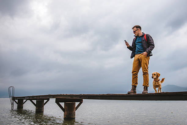 mann steht auf derander und benutzt smartphone - pier sea storm nature stock-fotos und bilder