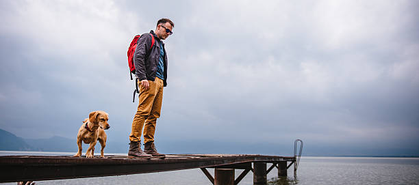 istock Man and his dog standing on wooden dock 579131668