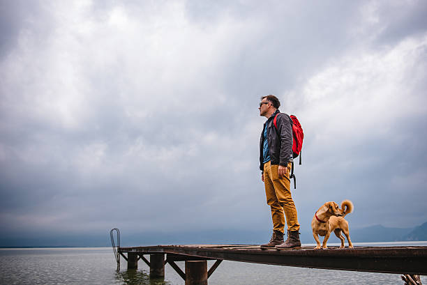 istock Man and his dog standing on wooden dock 579131716