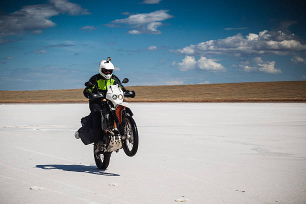 istock Man pulls wheelie by motorbike on salt pan. 579132026