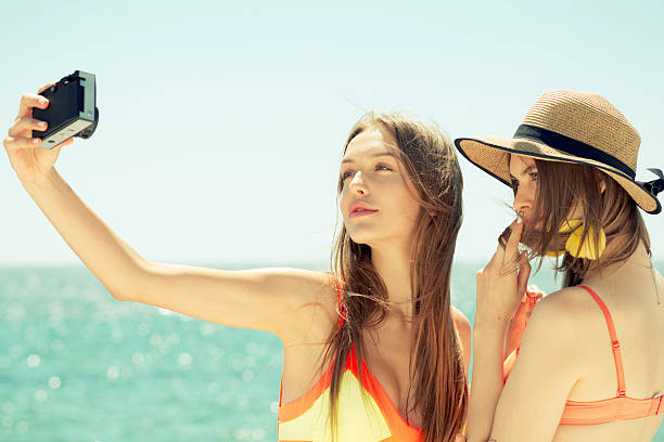 istock two smiling young women on beach making selfie 579133446