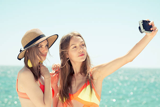 istock two smiling young women on beach making selfie 579133654