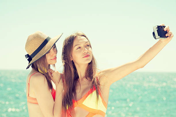 istock two smiling young women on beach making selfie 579133706