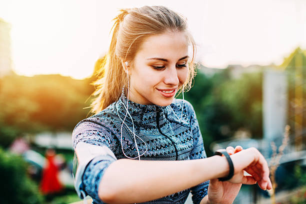 Young sportswoman checking her smart watch Portrait of a young woman in sports wear and with portable information devices outdoors at urban setting pedometer photos stock pictures, royalty-free photos & images
