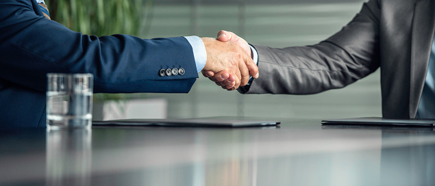 Two smiling mature businessmen shaking hands in office